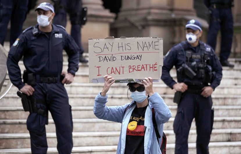 Una mujer aguanta un cartel mientras más manifestantes llegan para reclamar que "las vidas negras importan" en Australia. (AP)