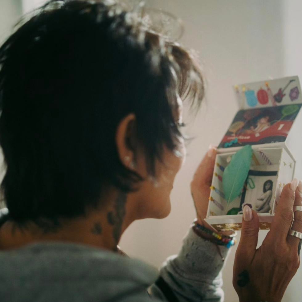 Alejandra Guzmán observa una foto de cuando estaba embarazada de Frida Sofía, en esta imagen que compartió del vídeo musical de su nuevo tema.