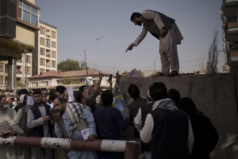 Los afganos se reúnen frente a una oficina de pasaportes del gobierno reabierta recientemente después de que los talibanes anunciaron que emitirían una acumulación de solicitudes aprobadas por la administración anterior en Kabul, Afganistán.