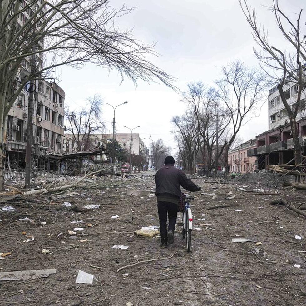 Un hombre camina con una bicicleta en una calle dañada por los bombardeos en Mariúpol, Ucrania, el 10 de marzo de 2022.