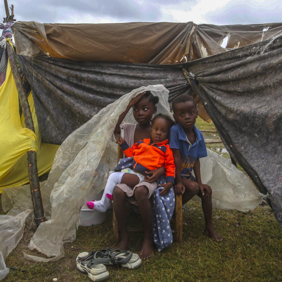Earthquake-displaced children huddle under a piece of plastic the morning after Tropical Storm Grace swept over Les Cayes, Haiti, Tuesday, Aug. 17, 2021, three days after a 7.2-magnitude earthquake. (AP Photo/Joseph Odelyn)