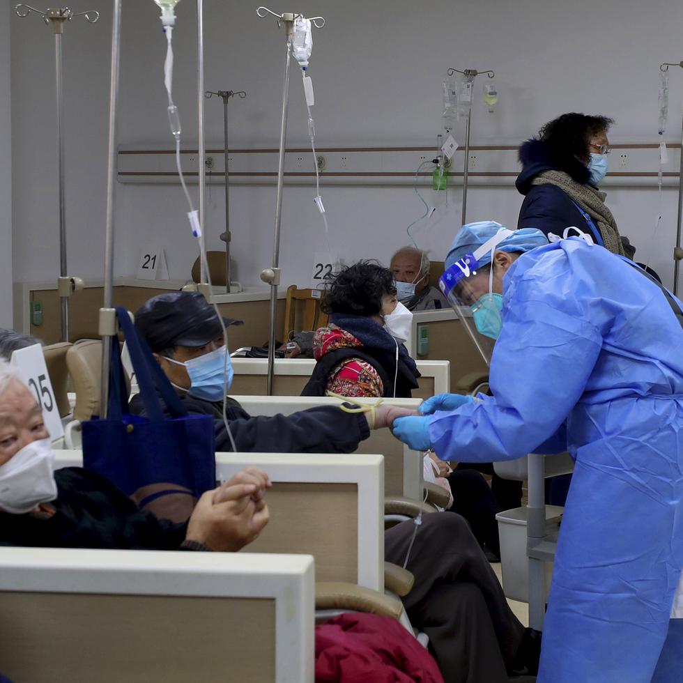 En esta foto publicada por la Agencia de Noticias Xinhua, un trabajador médico ayuda a un paciente con el goteo intravenoso en una institución de salud comunitaria en Shanghái, China.