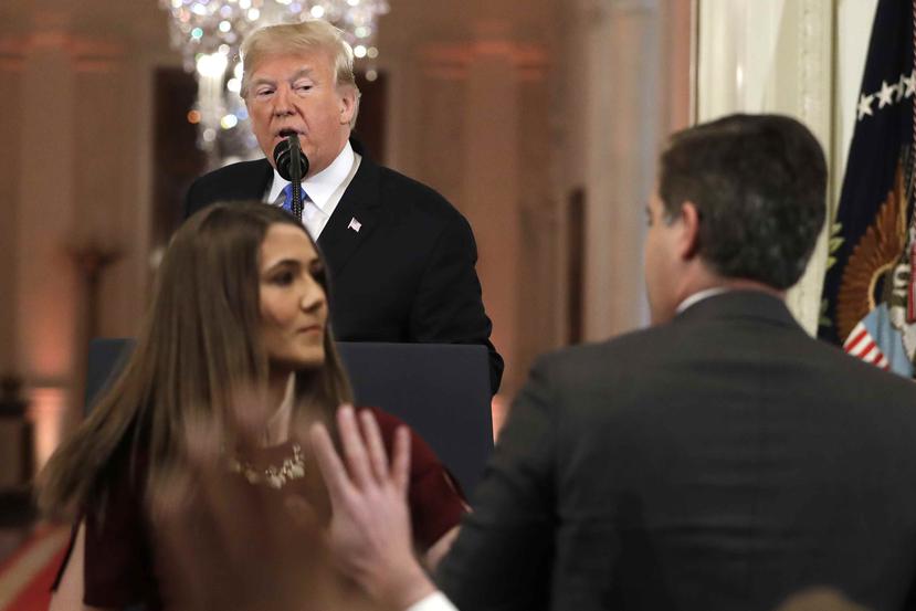 Una ayudante de Casa Blanca intenta quitarle el mocrófono a Acosta. (AP)
