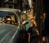 Un niño juega cerca de un carro viejo en la Habana Vieja, Cuba.
