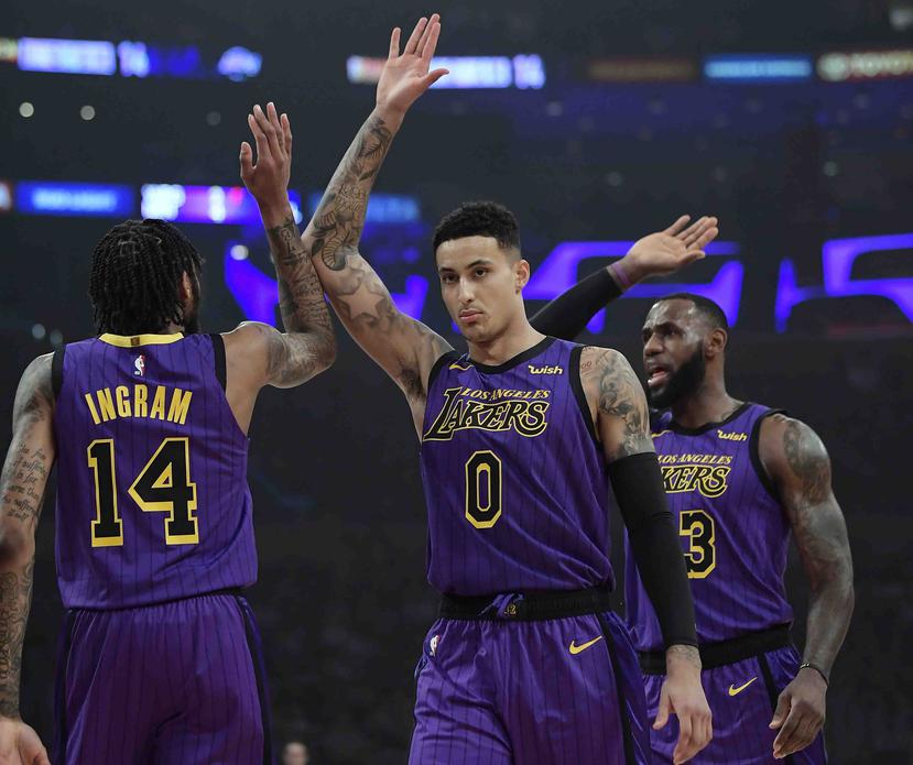 El jugador de los Lakers de Los Ángeles Brandon Ingram (izquierda) recibe la felicitación de sus compañeros Kyle Kuzma (centro) y LeBron James tras anotar una canasta en la primera mitad del juego el 23 de noviembre de 2018, en Los Ángeles. (AP/Mark J. Te