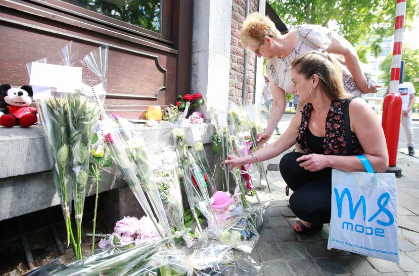 Varias personas colocan flores como homenaje a las víctimas del tiroteo ante el Café 'Les Augustins', de Lieja, Bélgica (AP).