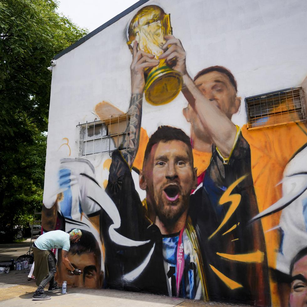 El artista Maxi Bagnasco pinta su mural con la imagen del astro Lionel Messi alzando la Copa de Mundo en Buenos Aires, Argentina, el jueves 22 de diciembre de 2022.