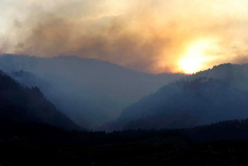 Al ponerse el sol, humo sube de un área incendiada al oeste de la subdivisión Falls Creek Ranch. (AP)