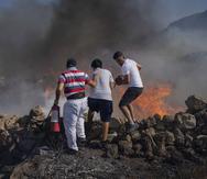 Vecinos intentan extinguir un incendio cerca del balneario de Lindos, en la isla griega de Rodas en el mar Egeo, 24 de julio de 2023. (AP Foto/Petros Giannakouris)
