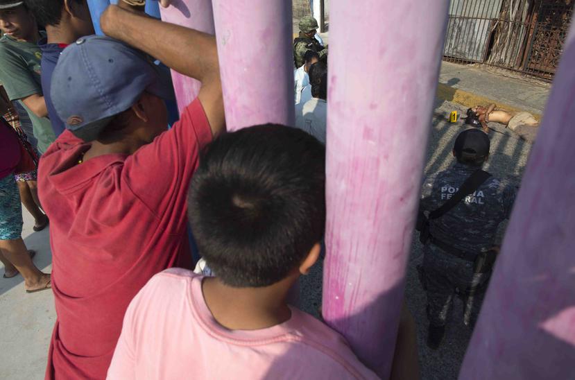 Niños observan a un policía federal que inspecciona una escena de un crimen ocurrido el pasado 12 de mayo en el vecindario El Coloso, en Acapulco, Mexico. (AP)