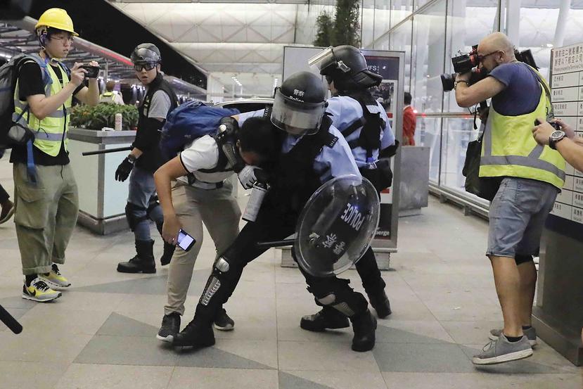 Policías antimotines arrestan a un manifestante durante una protesta en el Aeropuerto de Hong Kong. (AP)