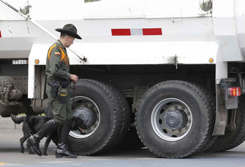 Tras el atentado de la semana pasada en Colombia, un guardia verifica junto a un perro un camión.  (AP)