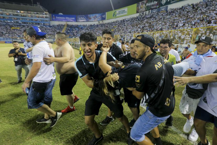 Un grupo de hinchas carga a un aficionado herido hacia la cancha del estadio de Cuscatlán en San Salvador.