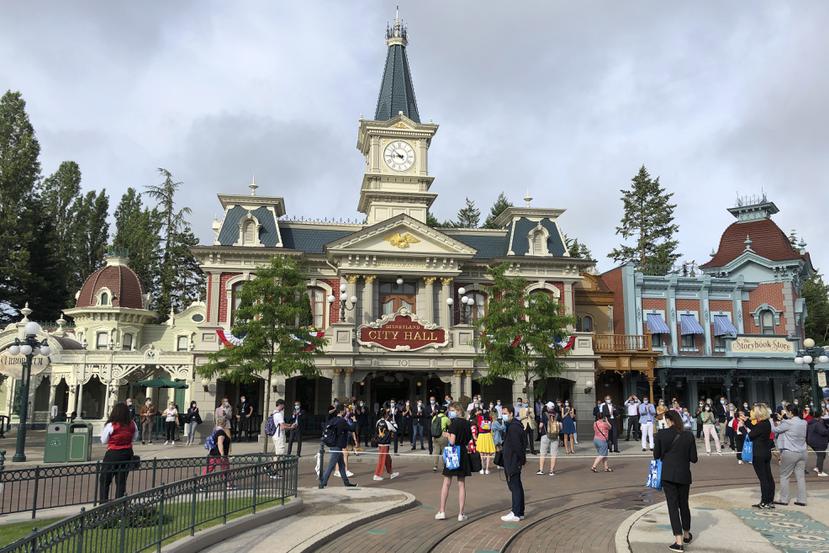 Visitantes al parque de diversiones Disneyland Paris esperan fuera del recinto a su apertura.