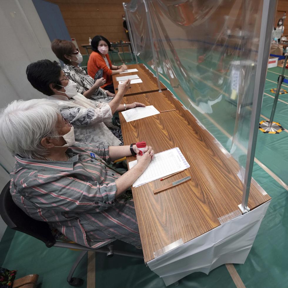 Personal de una comisión electoral local, en Tokio, observa a una persona emitir su voto en las elecciones de Japón, el 10 de julio de 2022.