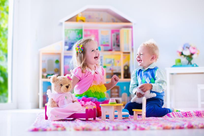 Menores jugando con una casa de muñecas.