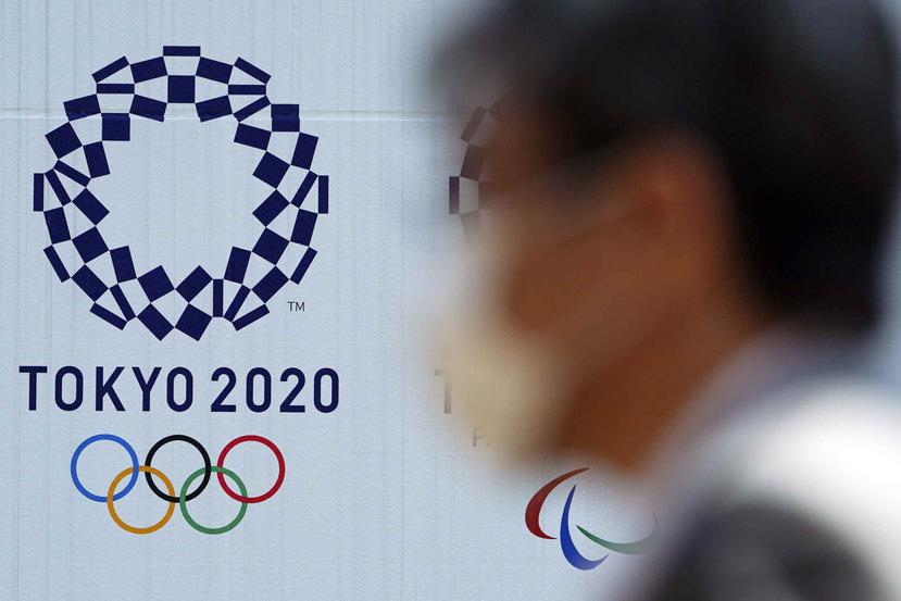 Un hombre con una mascarilla pasa por delante del logo de los Juegos Olímpicos de Tokio 2020, en Tokio. (AP)