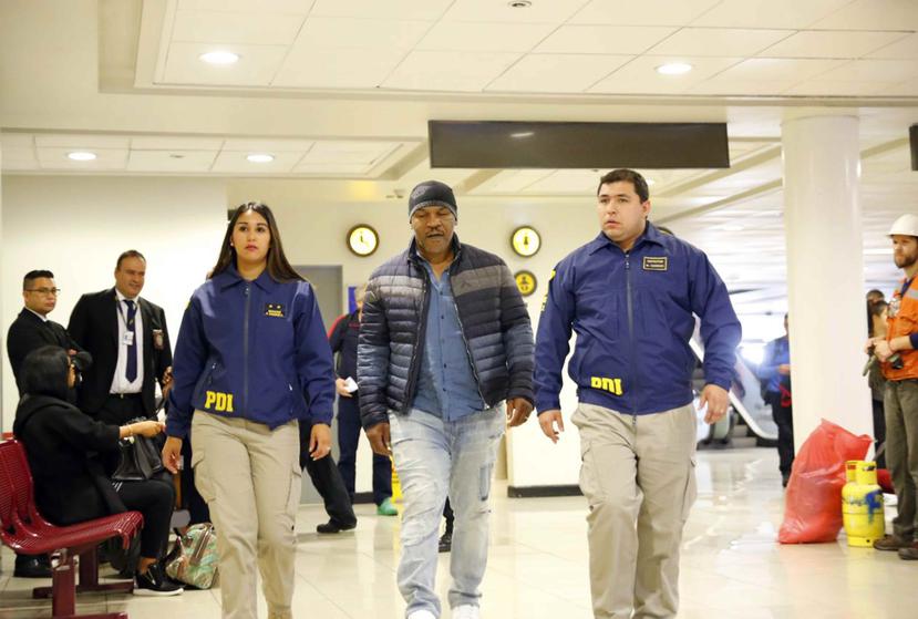 El excampeón mundial Mike Tyson es escoltado por dos agentes de la Policía de Investigaciones (PDI) a su llegada a un aeropuerto en Chile. (AP / Esteban Félix)
