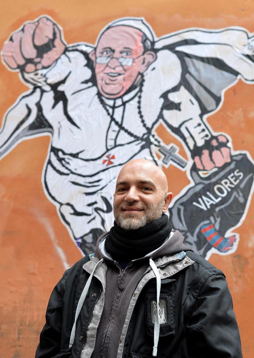 El artista italiano Mauro Pallotta posa al lado del grafiti en el que ha retratado al papa Francisco con estética de "superhéroe", en la calle Plauto, en Roma (EFE/Ettore Ferrari).