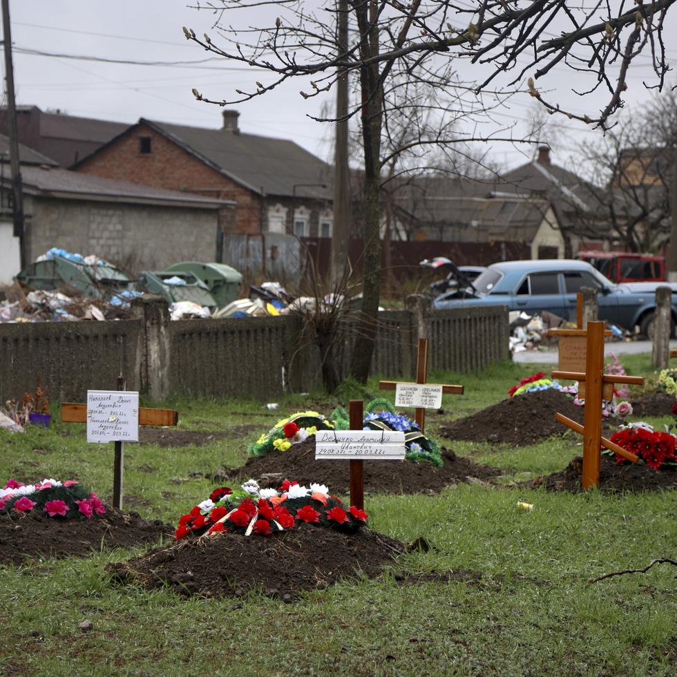 Tumbas de residentes que fallecieron durante los combates contra Rusia en una calle detrás de viviendas de la ciudad de Mariúpol, Ucrania.