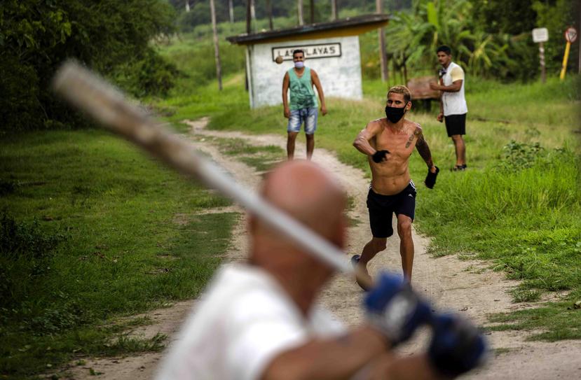 Personas con mascarillas juegan pelota en el vecindario de Las Playas, al este de La Habana. (AP)