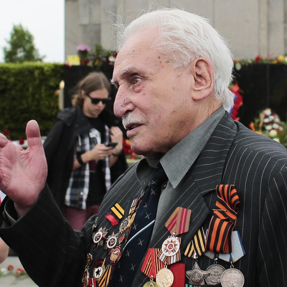 En esta imagen del viernes 8 de mayo de 2015, David Dushman, de 92 años, veterano de guerra de la ex Unión Soviética, habla con personas que ondean banderas ucranianas durante una ceremonia en el Monumento de Guerra Soviético en el Tiergarten, en Berlín, Alemania.