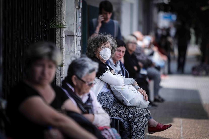 Personas hacen fila afuera de un banco donde pagan jubilaciones y planes sociales este viernes, en Buenos Aires, Argentina. (EFE)