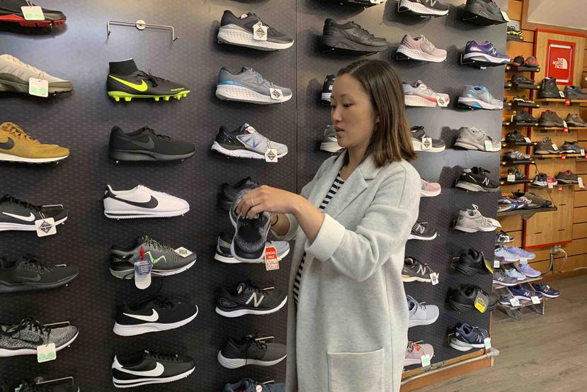 Jennifer Lee, cuya familia es propietaria de la tienda de zapatos Footprint en San Francisco, observa un zapato tenis junto a una pared llena de ellos, muchos de los cuales son fabricados en China y estarán sujetos a nuevos aranceles estadounidenses a par