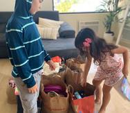 Diego y Mila organizan los juguetes y la ropa que han recibido como donativos de otras personas. (Suministrada)