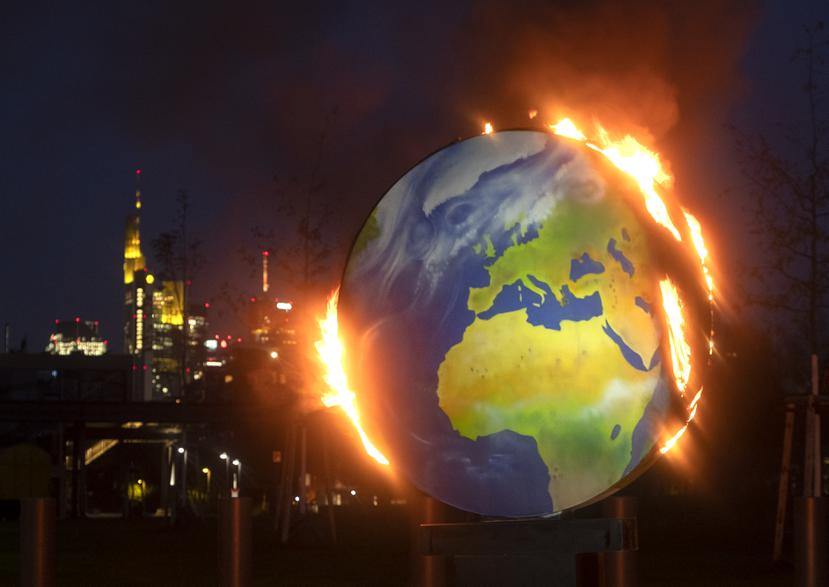 Una figura del planeta Tierra arde ante la sede del Banco Central Europeo en Fráncfort, Alemania.
