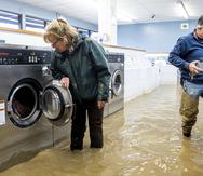 Pamela y Patrick Cerruti sacan monedas de la lavandería Pajaro Coin Laundry en medio de una inundación, el martes 14 de marzo de 2023, en la comunidad de Pajaro, condado Monterey, California.