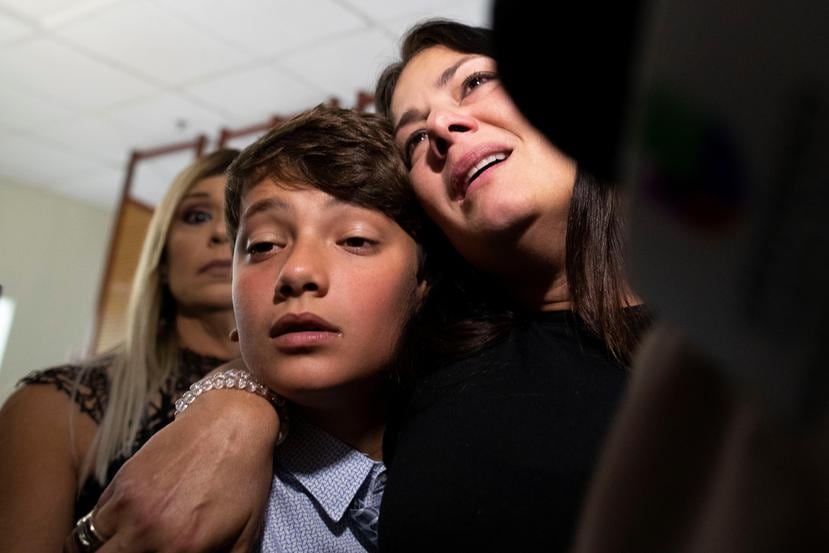 La hermana de Héctor Ferrer, Marinelli Ferrer, abraza al hijo menor del fenecido líder político, Eduardo, de 12 años.