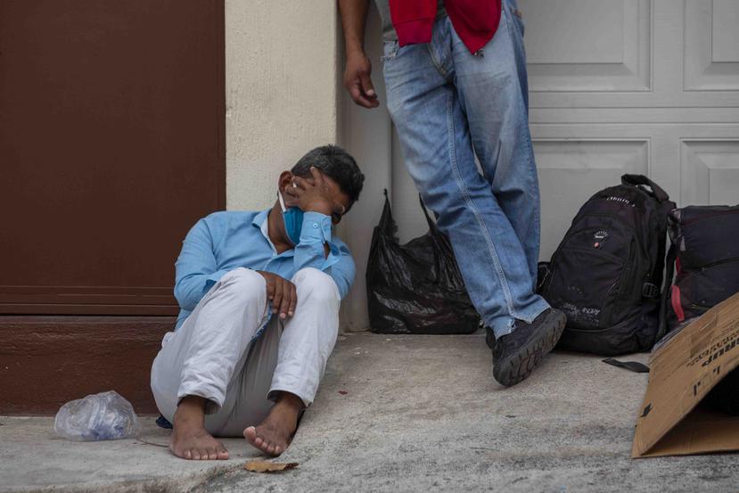 Un indigente con una mascarilla en una calle de Ciudad de Guatemala espera por entrar a un albergue. (AP)