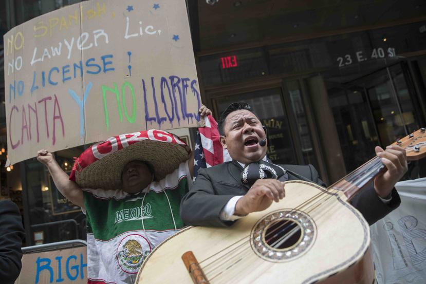 Un manifestante baila y canta con un mariachi durante una protesta al otro lado de la calle donde está el edificio que alguna vez albergó la oficina del abogado Aaron Schlossberg el viernes 18 de mayo de 2018. (AP)