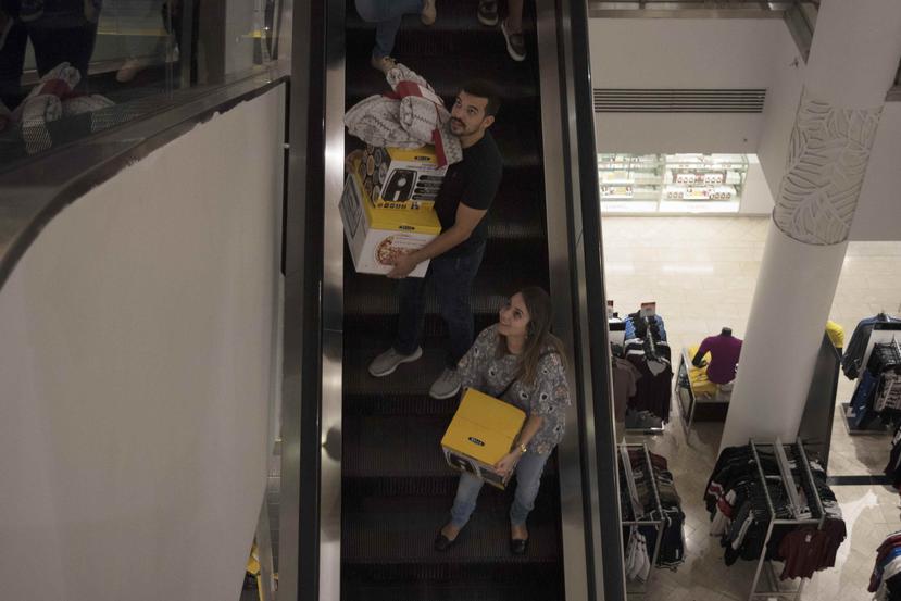 Dos personas bajan las escaleras de Macy's con varios Air Fryer.