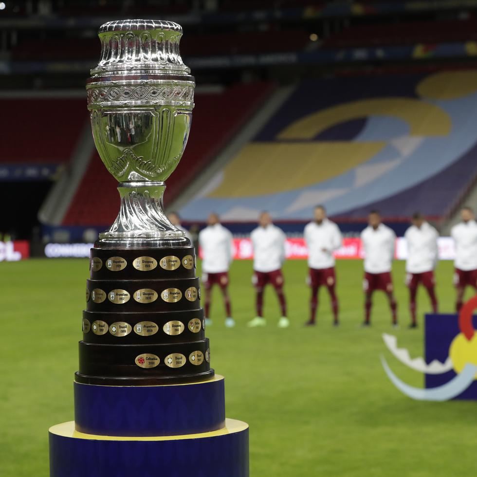 La foto muestra el trofeo de la Copa América delante de los jugadores de Venezuela durante la interpretación de los himnos nacionales, previo al partido inaugural entre ese equipo y Brasil.