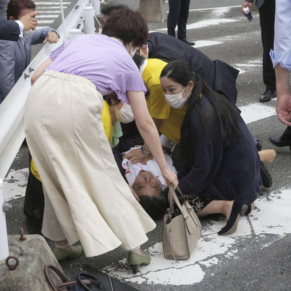 El ex primer ministro de Japón Shinzo Abe, centro, cae al suelo en Nara, en el oeste de Japón.
