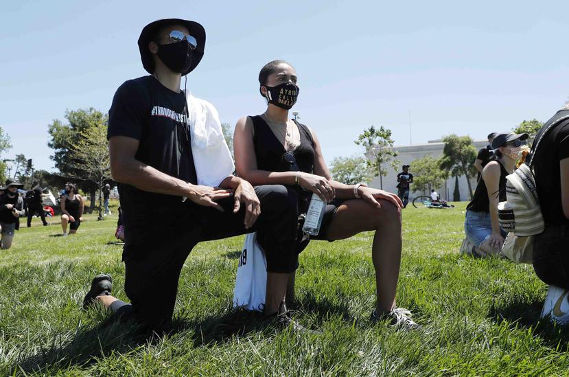 Stephen Curry y Ayesha Disa, esposa del canastero, se arrodillan durante un protesta en Oakland. (AP)