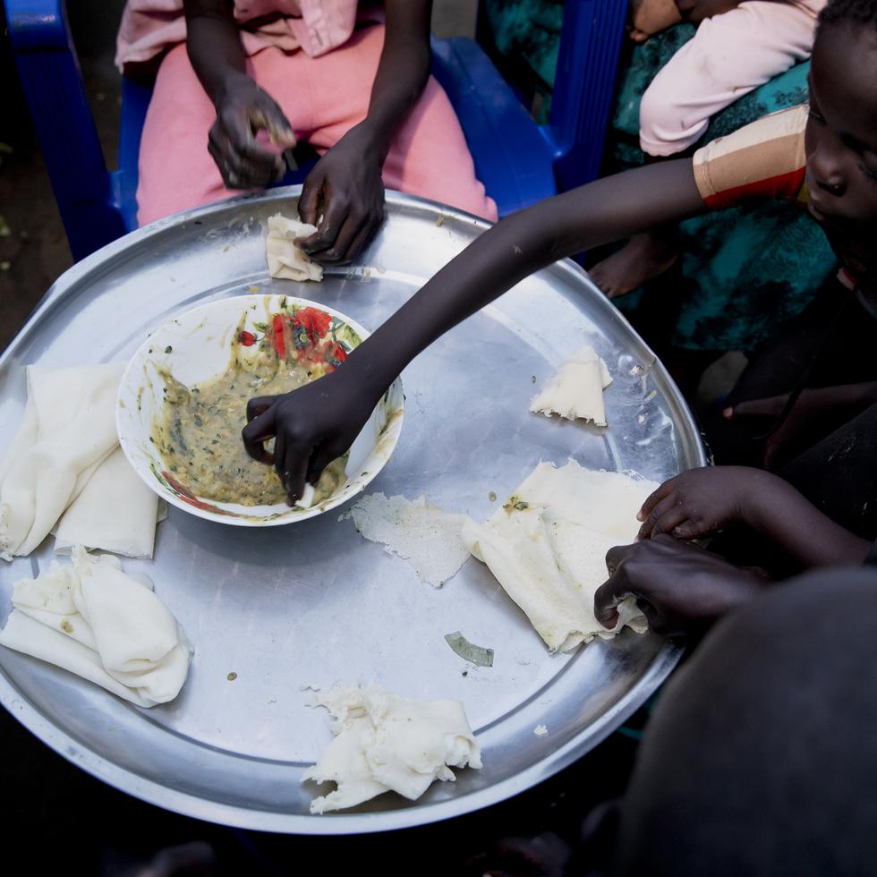 Paska Itwari Beda, que tiene cinco hijos de menos de 10 años, comparte una comida, quizá la única del día, con su familia en su casa en Juba, Sudán del Sur, el martes 27 de mayo de 2021.