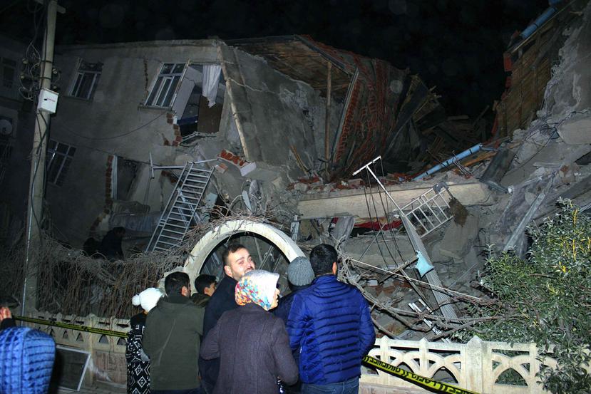Personas observan un edificio derrumbado tras un sismo de magnitud 6.8 en la ciudad de Elazig, en el este de Turquía. (IHA vía AP)
