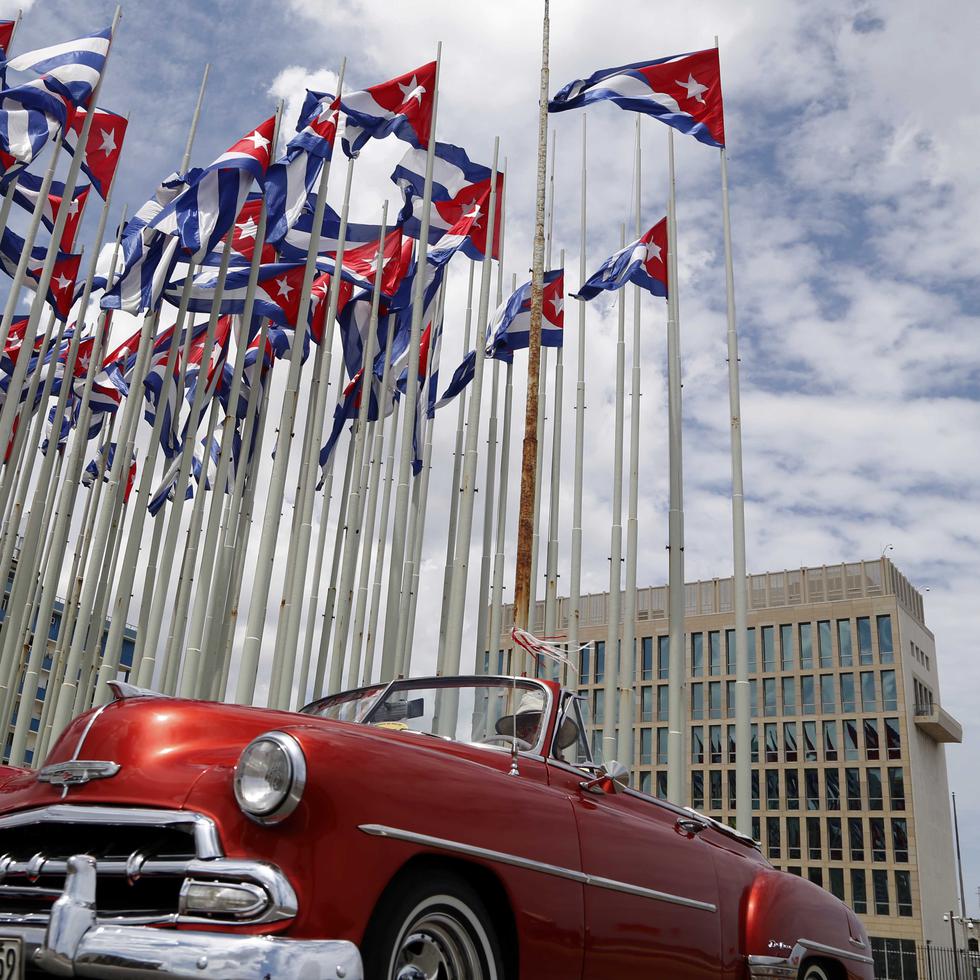 En esta imagen de archivo, un auto descapotable clásico estadounidense pasa junto a la embajada de Estados Unidos mientras las banderas cubanas ondean en la Tribuna Antiimperialista, en el Malecón, en La Habana, Cuba.