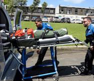 Los paramédicos Luis O. García  y Jonathan Pinto colocan una camilla en una ambulancia.