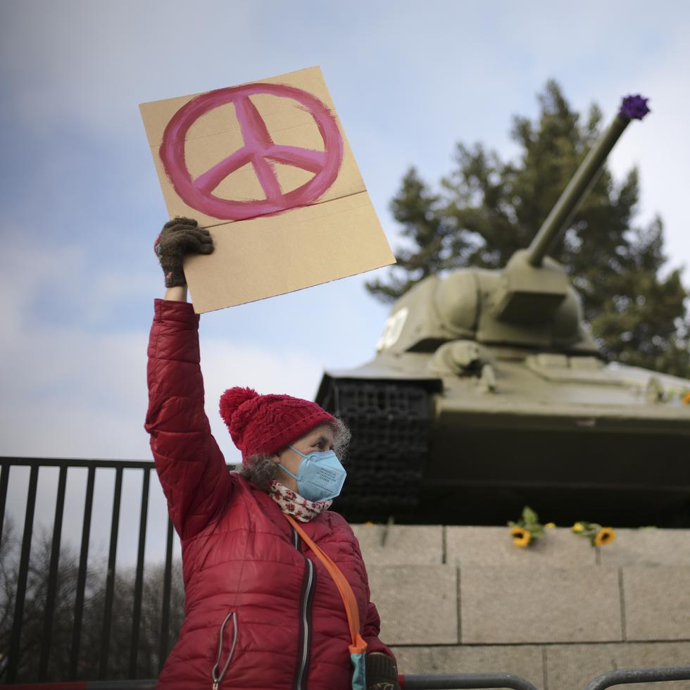 A woman shows a peace sign in front of a Russian WWII tank at the Soviet War Memorial at the bolevard 'Strasse des 17. Juni' alongside a rally against Russia's invasion of Ukraine in Berlin, Germany, Sunday, Feb. 27, 2022. (AP Photo/Markus Schreiber)