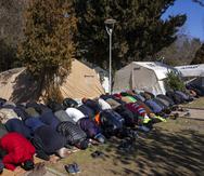 Desplazados por el terremoto asisten a la oración del viernes en un campamento en Kahramanmaras, Turquía, el viernes 17 de febrero de 2023.  (AP Foto/Bernat Armangue)