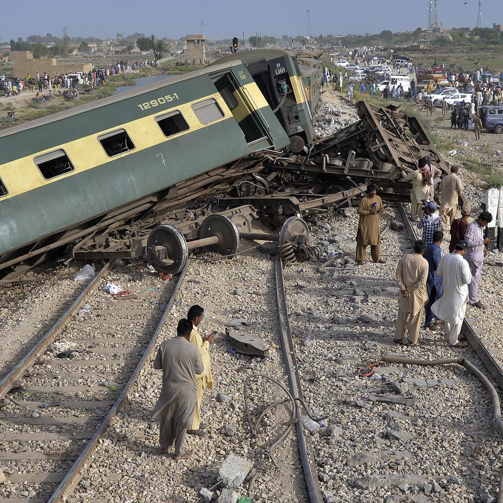 Civiles observan los vagones dañados de u tren de pasajeros que se descarriló cerca de Nawabshah, Pakistán, el domingo 6 de agosto de 2023.