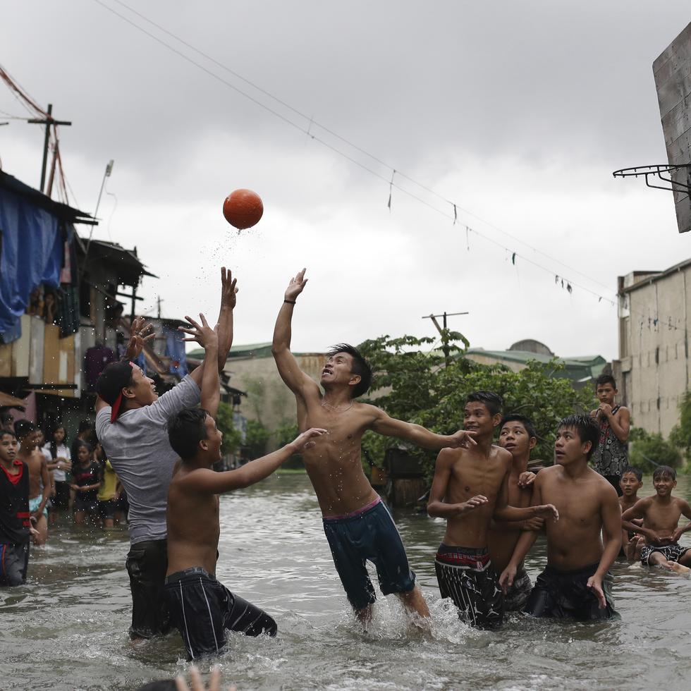 Jovencitos filipinos juegan baloncesto hasta en calles inundadas de la villa costera Malabon, al norte de Manila, en Filipinas.