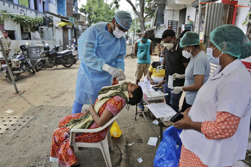 Un trabajador de la salud le hace una prueba de COVID-19 a una mujer en una calle de Ahmedabad, India.