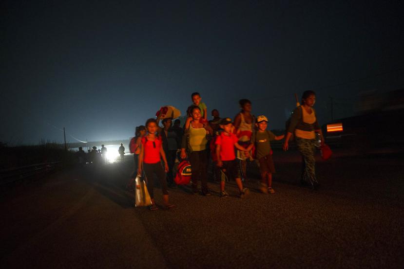 Una familia camina junto a otros migrantes centroamericanos en una caravana de miles de personas que lentamente se dirige a la frontera entre México y Estados Unidos, en las afueras de Arriaga, México, antes del amanecer del sábado 27 de 2018. (AP Foto/Ro