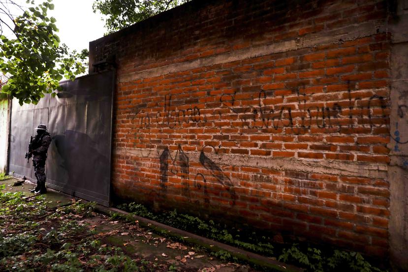 En esta imagen de archivo, tomada el 10 de octubre de 2019, un agente de policía hace guardia junto a una pared durante una patrulla rutinaria en El Salvador. (AP)