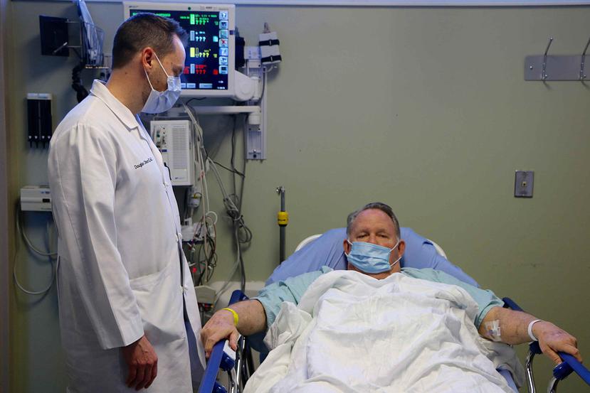 El doctor Doug Olson conversa con el paciente William Ness, de 70 años, enfermo de gripe y quien fue trasladado a la sala de emergencia del hospital Northside en Cumming, Georgia. (AP)